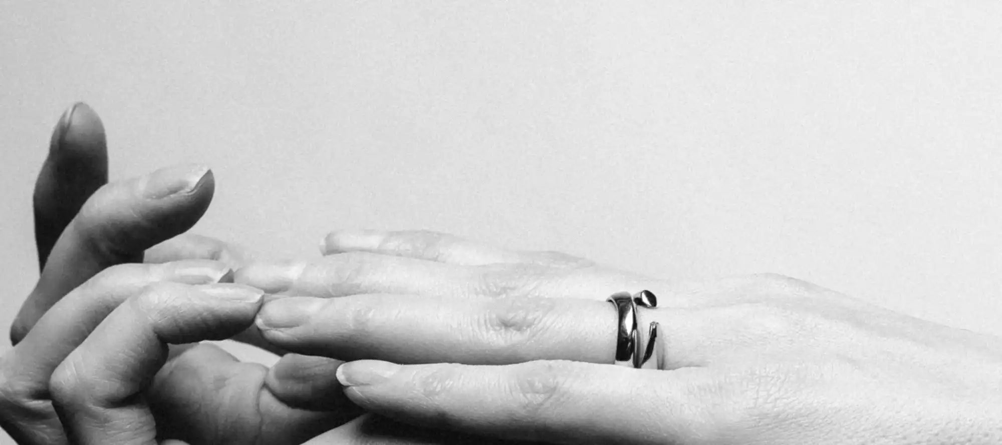 Intertwined hands with a modern ring.