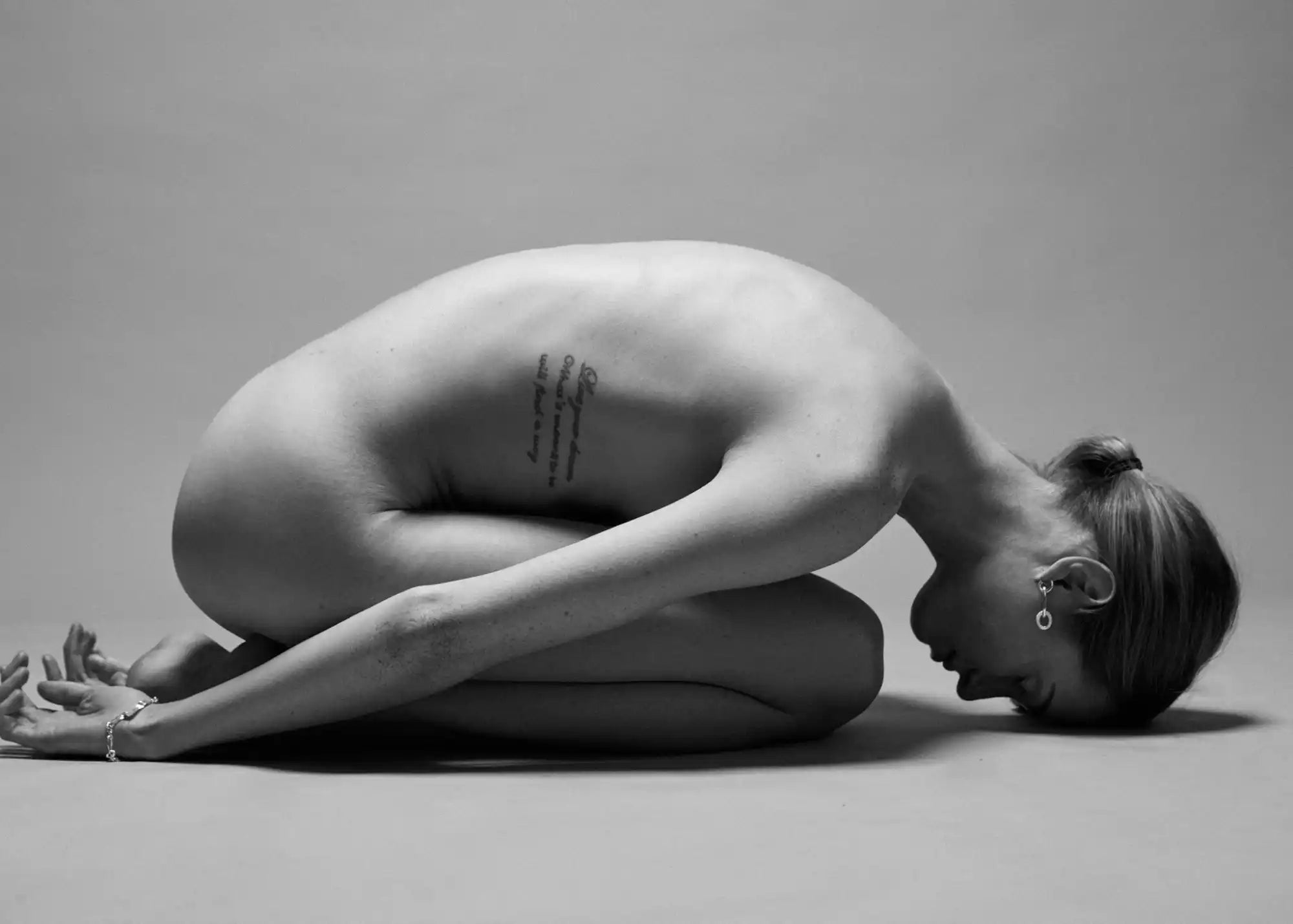 Nude woman in child’s pose.