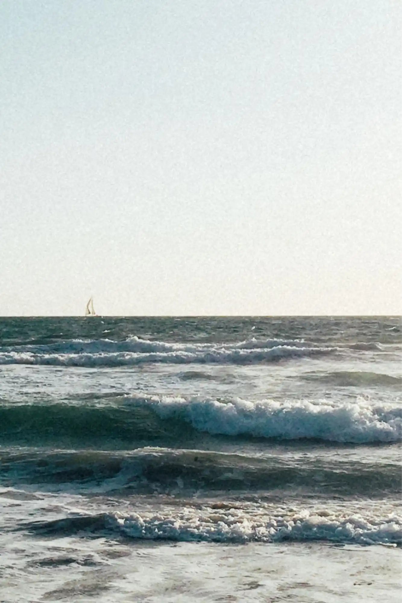 Ocean waves with distant sailboat.