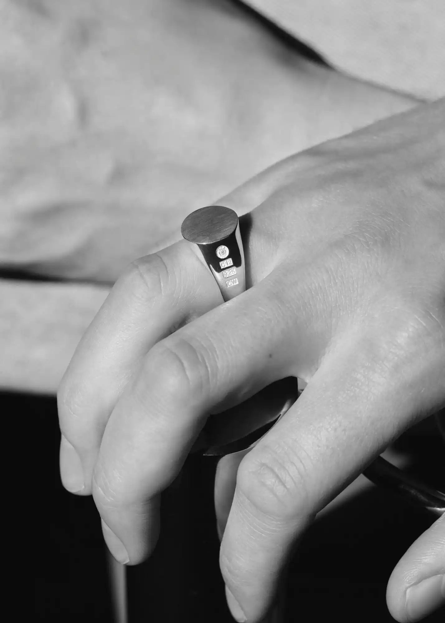A person’s hand wearing a silver signet ring with a small, round, flat top.