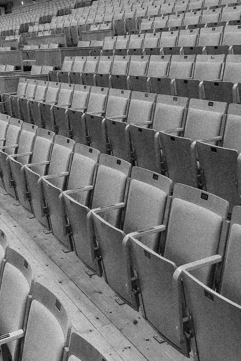 Rows of empty auditorium seats in monochrome.