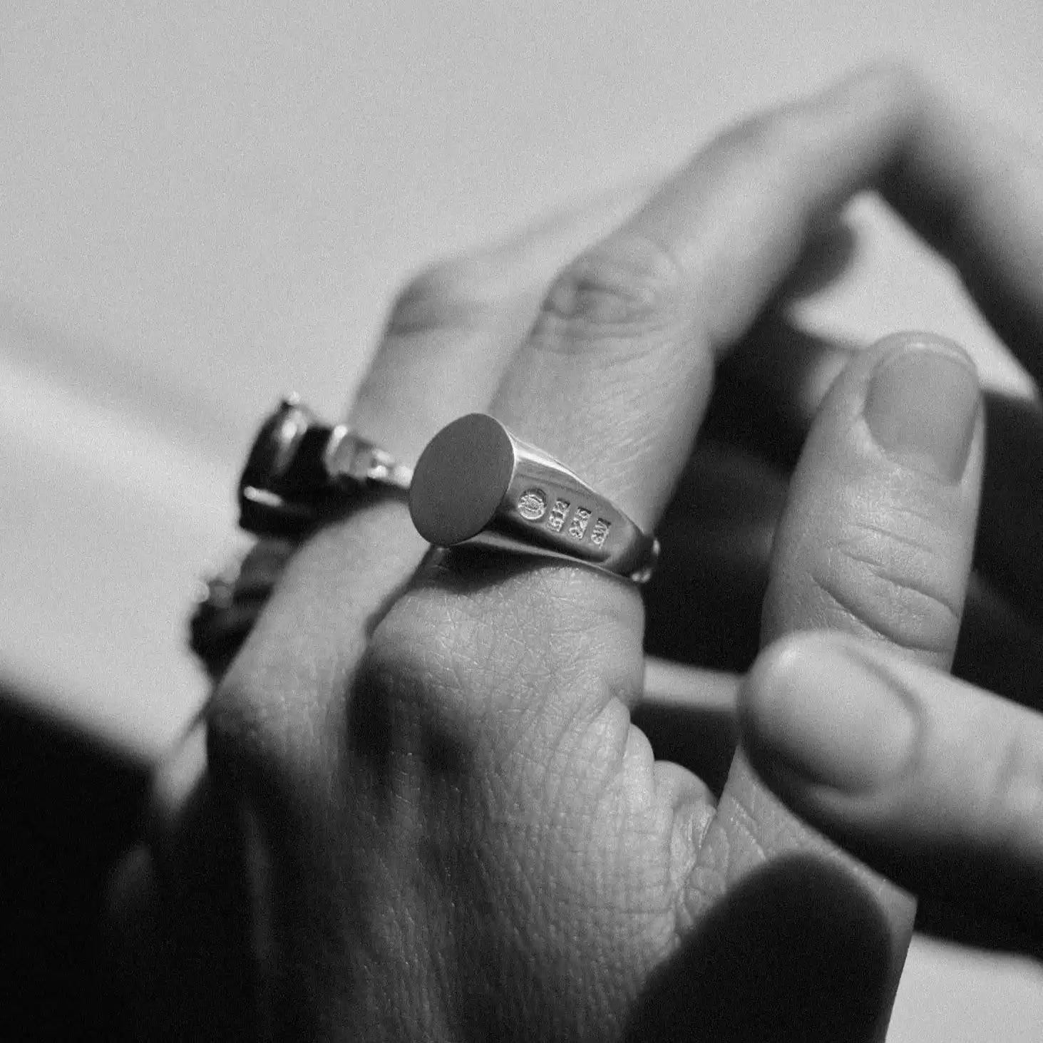 Silver signet ring with an oval face and three small clear stones.