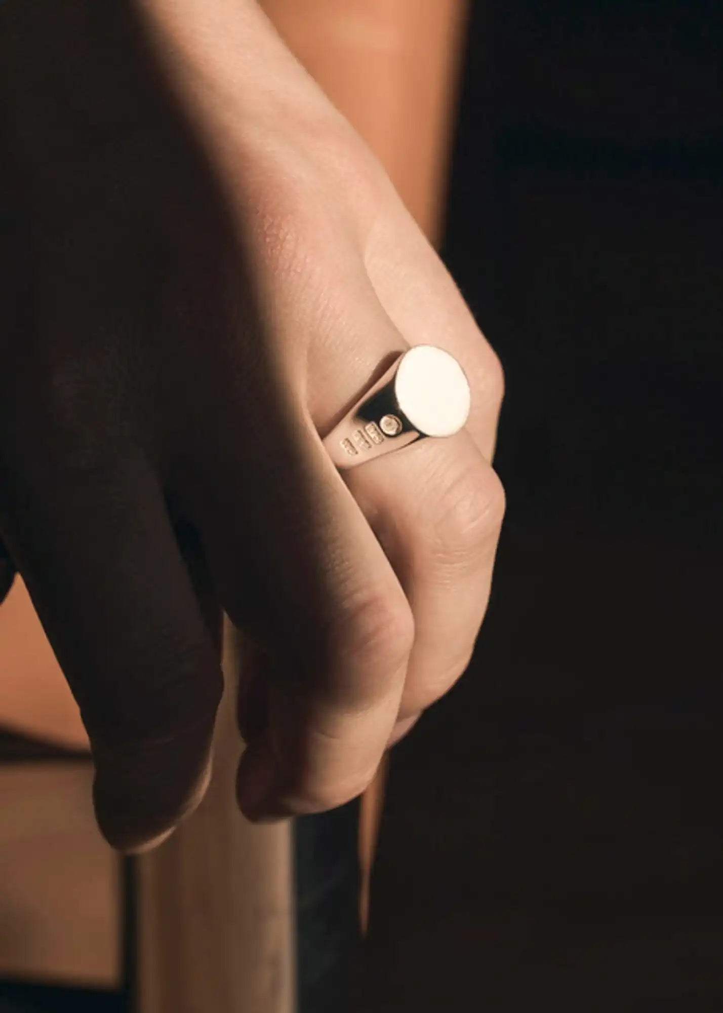 A silver signet ring with a smooth, round face and two small, clear stones on the band.