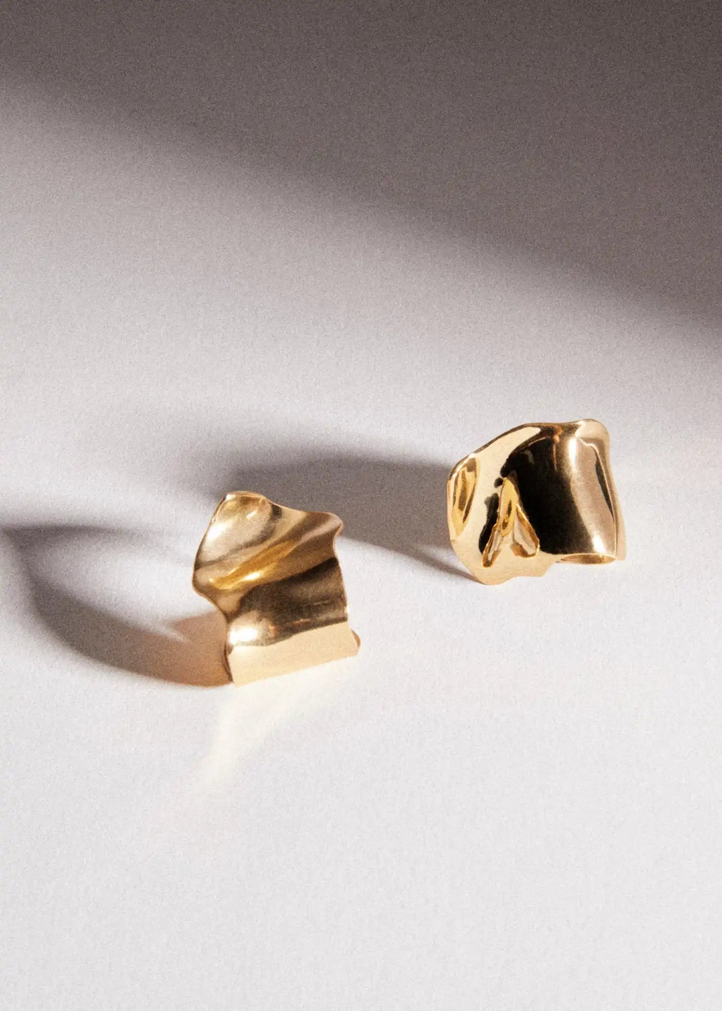 Two gold, abstract earrings.